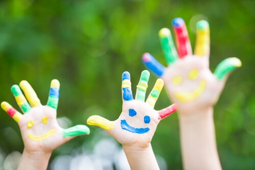 Manos de niños pintadas con caras sonrientes