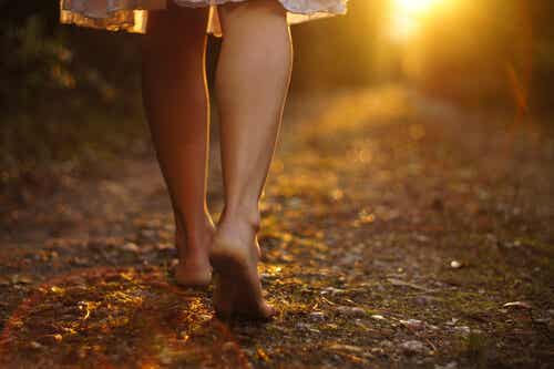Mujer descalza andando por un camino
