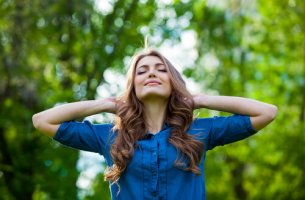 Mujer feliz con los ojos cerrados y las manos en la cabeza