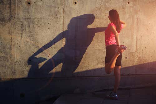 Mujer haciendo deporte con ganas apoyada en una pared