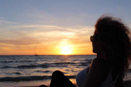 Mujer mirando una puesta de sol recordando