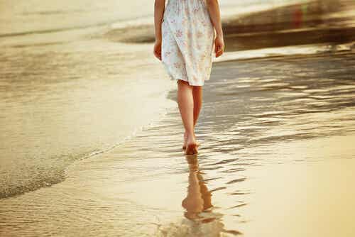 Mujer paseando por la arena de la playa descalza