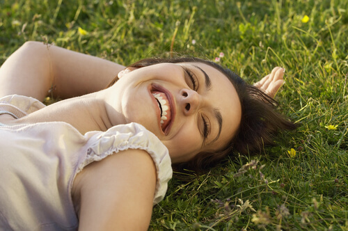 Mujer sonriendo tumbada en el césped