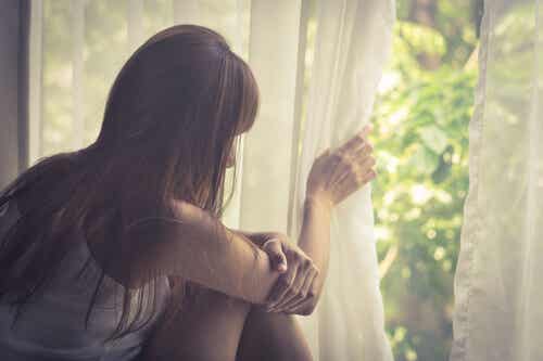 Mujer triste pensando en su vida mirando por la ventana