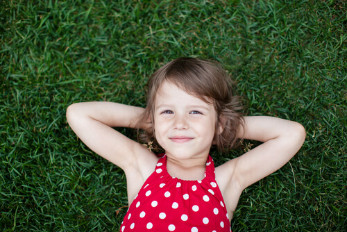 Niña feliz tumbada en el cesped