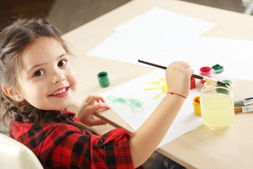 Niña pintando un dibujo con acuarelas