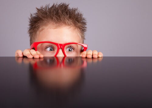 Niño con gafas rojas observando con curiosidad 