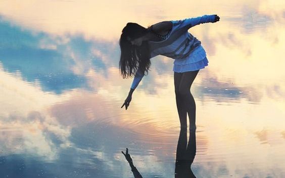 chica tocando su reflejo en el agua