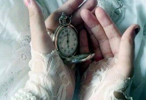 manos con un reloj que marca el presente