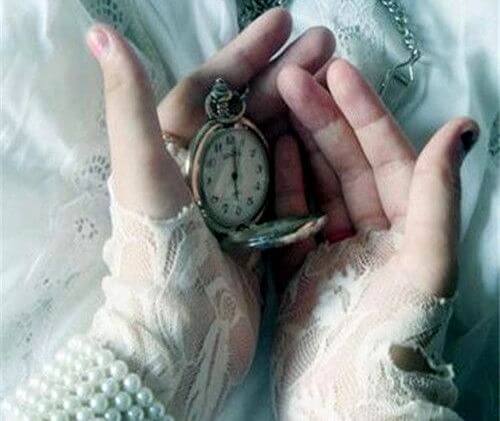 manos con un reloj que marca el presente