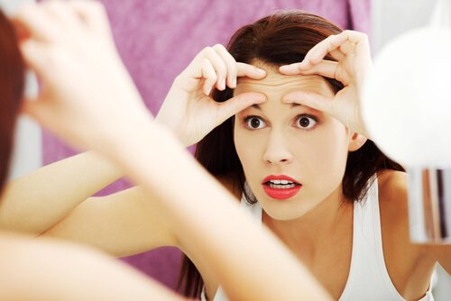 Mujer con miedo a envejecer mirándose a un espejo