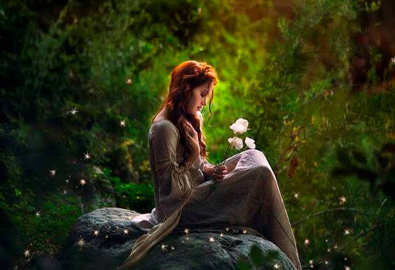 mujer en un bosque sujetando una flor