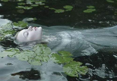 mujer en un río con nenúfares