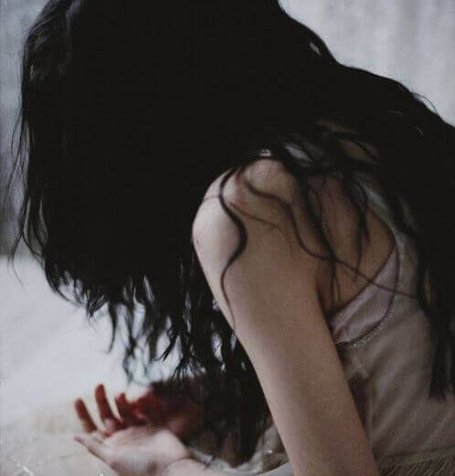 Mujer inclinada mirándose las manos