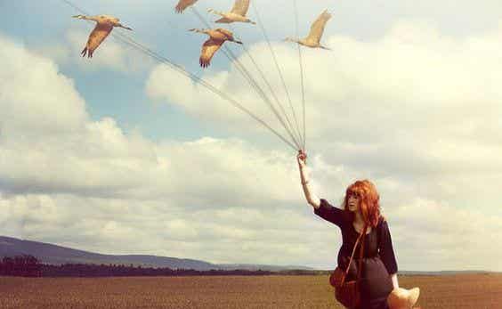 mujer sujetando una cometa en forma de pájaros