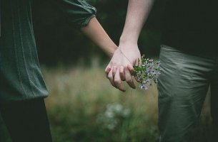 pareja cogida de las manos con ramo de flores