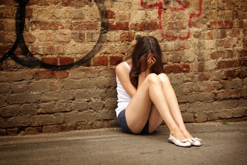 Chica adolescente con depresión sentada en el suelo