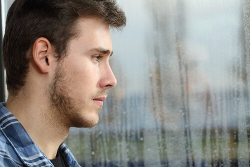 Chico adolescente mirando por la ventana