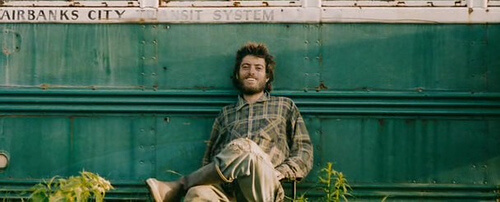 Christopher McCandless sentado apoyado en su caravana