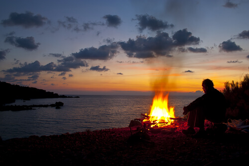 Hombre al anochecer con fuego a la playa