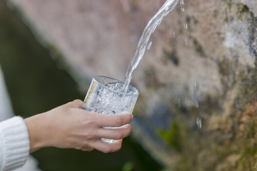 Mano sujetando un vaso llenándolo de agua