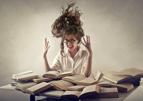 Mujer con estrés y muchos libros en la mesa