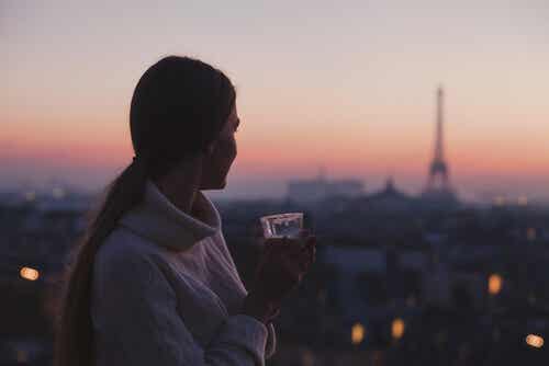 Mujer disfrutando de la vista de Paris con un vaso de café en la mano