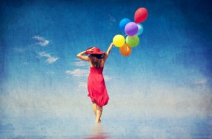 Mujer feliz caminando por el mar con globos de colores