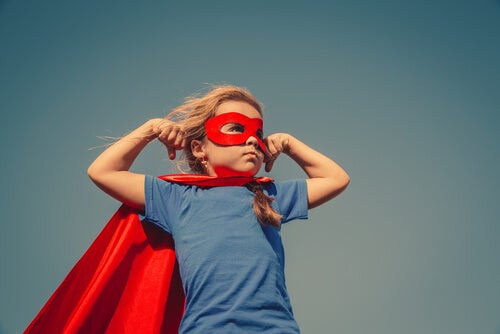 Niño vestido de superhéroe con una máscara y una capa rojas