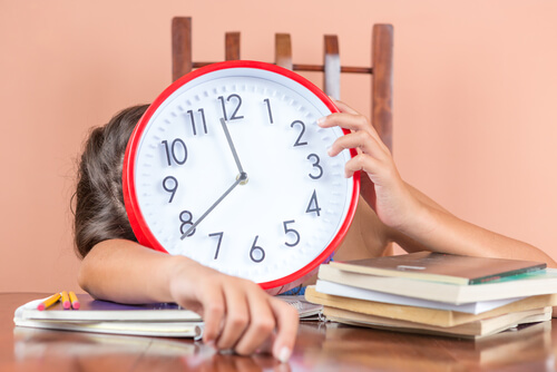 Niño con un reloj y muchos deberes