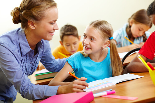 Profesora ayudando a su alumna en clase con las tareas