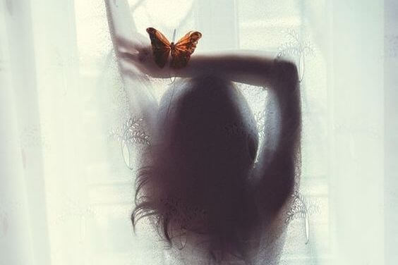 mujer con mariposa en la mano representando el amor que habita en el alma