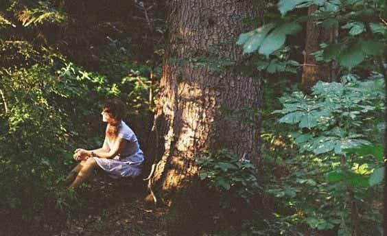 mujer sentada en el bosque pensando en su infelicidad