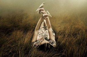 Mujer tumbada con pájaros en las manos