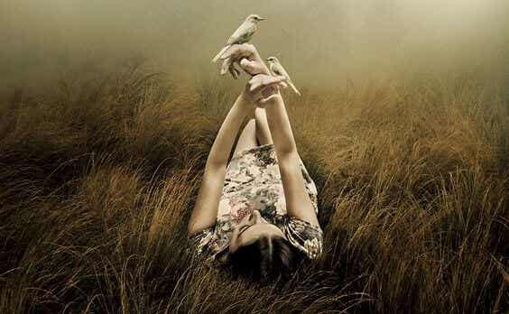 mujer tumbada con pájaros en las manos