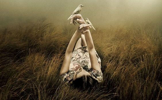 mujer tumbada con pájaros en las manos