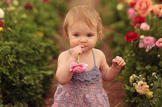 niña con flores disfrutando de los olores de infancia