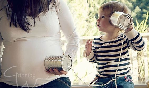 niño escuchando a su hermano en el embarazo de su madre