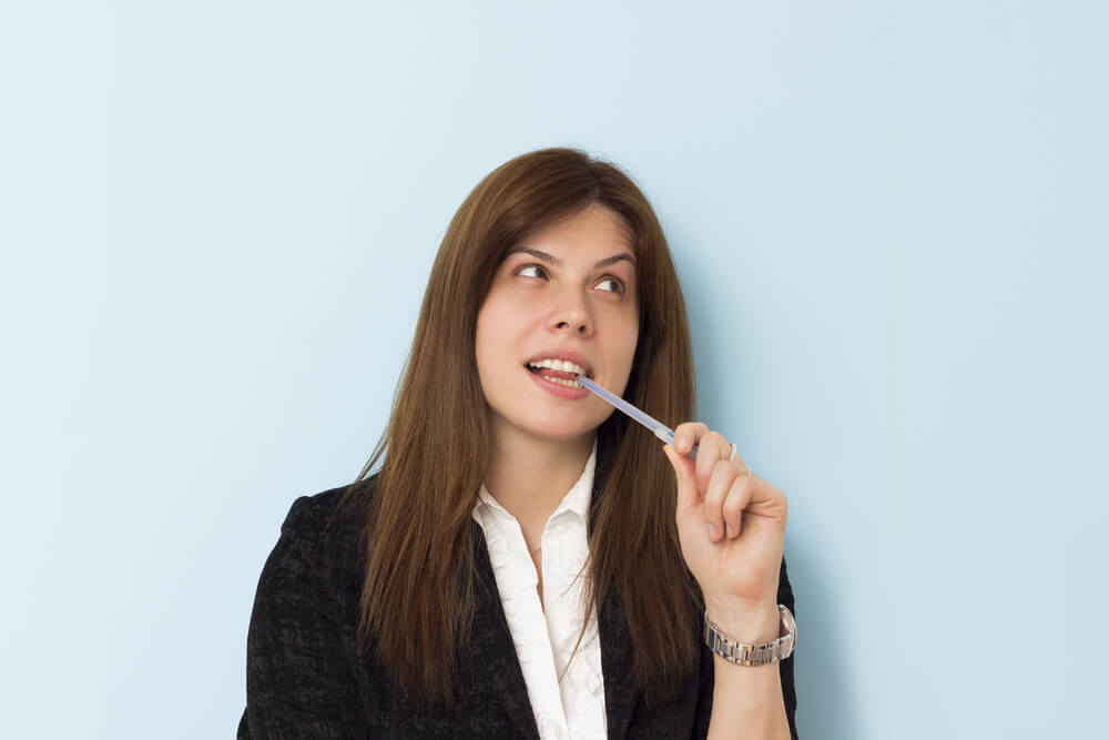 mujer mordiendo la tapa de un boli