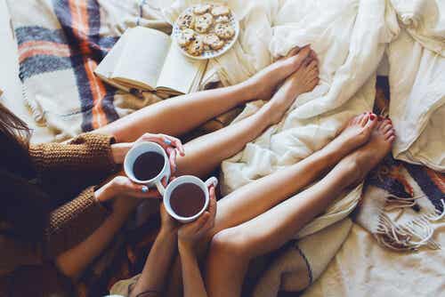 Amigas sentadas en la cama tomando café