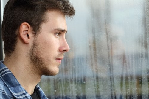 Adolescente triste mirando por la ventana