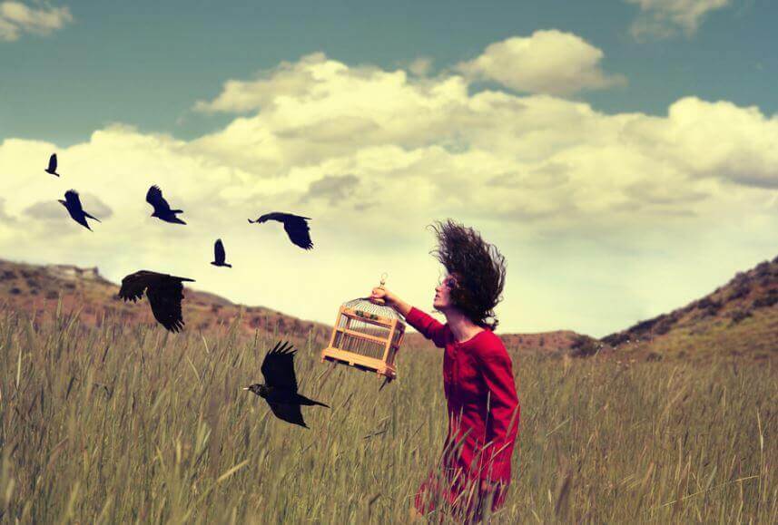Mujer liberando pájaros de una jaula