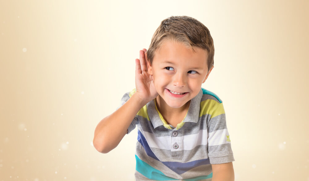 Niño con la mano en la oreja escuchando