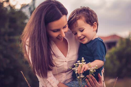 Madre cogiendo a su hijo en brazos mientras miran una flor