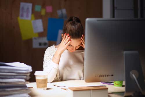 Mujer cansada sentada frente a su ordenador en el trabajo