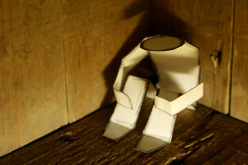 Muñeco de papel sentado en una esquina