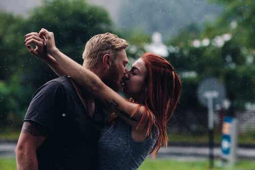 Pareja dándose un beso bajo la lluvia