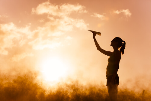 Mujer imaginando con un avión de papel