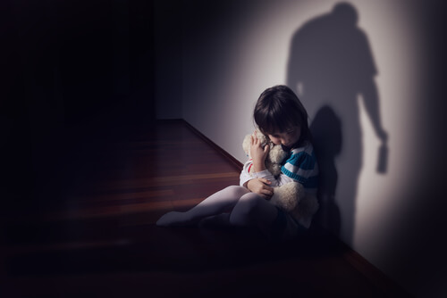 Niño con miedo al lado de la pared