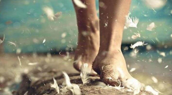 Pies caminando sobre la arena y las plumas